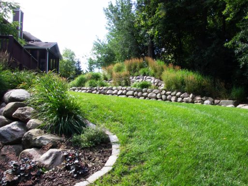 A landscaped garden featuring stone walls, grassy areas, and shrubs.