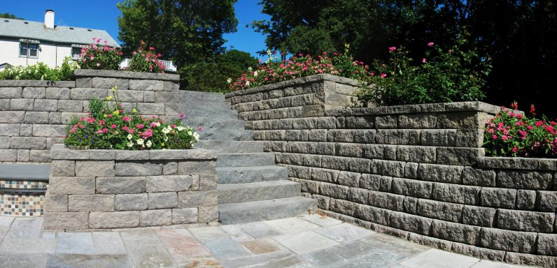 Stone steps leading up to a landscaped area with blooming flowers and greenery.