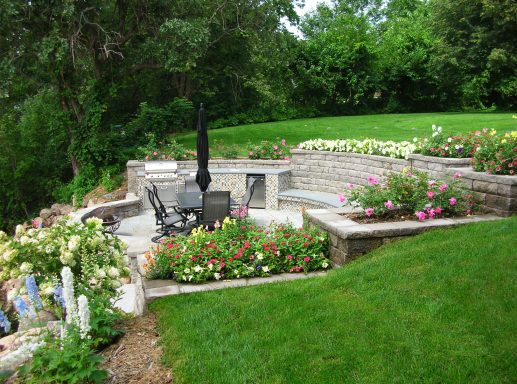 A landscaped garden with seating area surrounded by flowers and greenery.