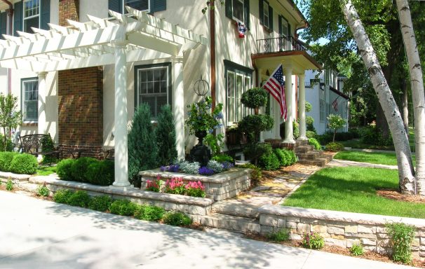 Charming house with a pergola, colorful garden, and American flag displayed outside.